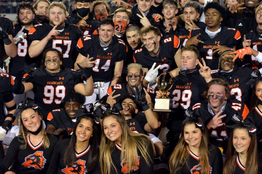 Football+players+and+cheerleaders+pose+with+the+BI-District+game+trophy+on+Dec.+12.
