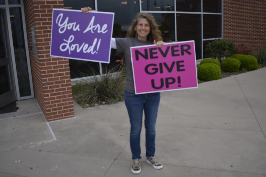 Volunteers hold signs of encouragement for students