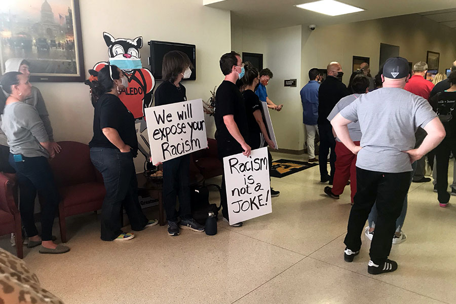 Two community members hold signs in the foyer of the administration building before Monday nights meeting.