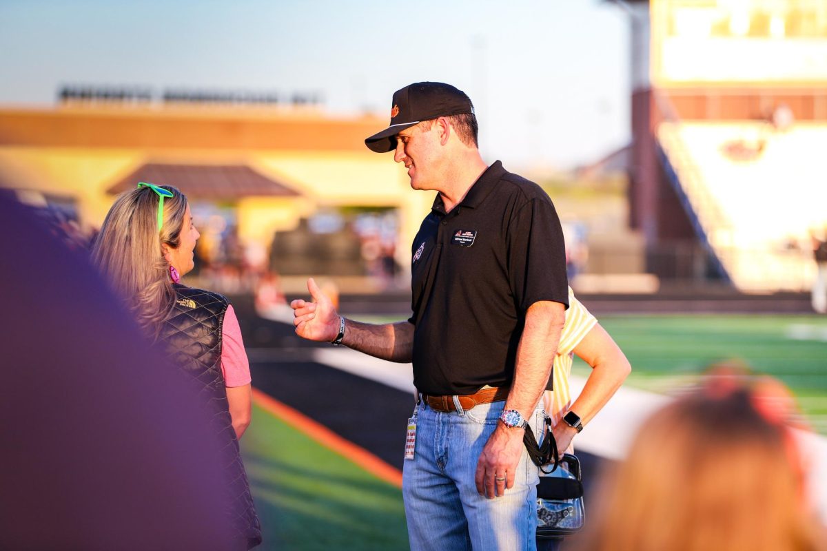 Before the varsity football game against Denton Ryan, principal Michael Martinak talks with varsity cheer coach Rhonda Psencik on the sidelines Friday, Oct. 4.