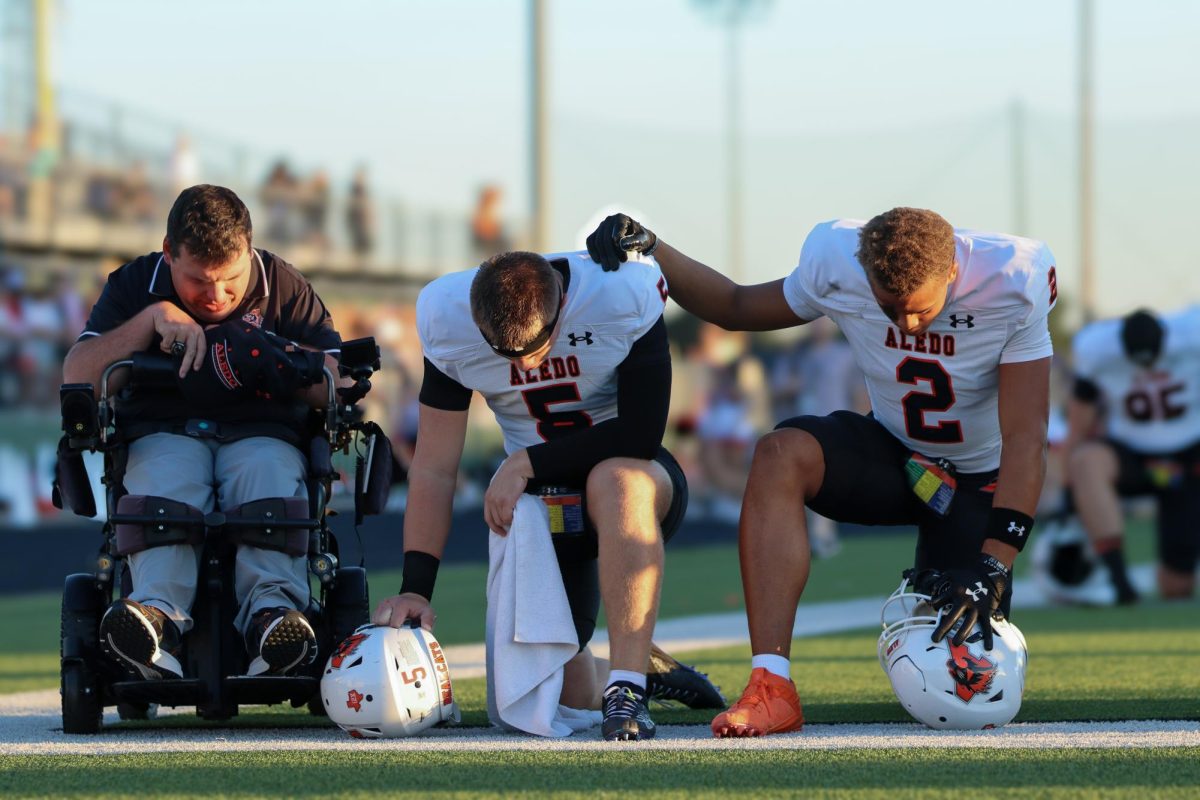 The bond of brothers. Junior quarterback Gavin Beard and junior wide receiver Kaydon Finley kneel with Brodie Sharp in prayer before the Aledo vs. Fossil Ridge game Friday, Sept. 26.