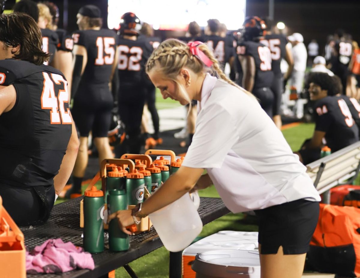 Lining up the bottles for the football team, senior Cady Hill prepares for the varsity football game on 10/4.